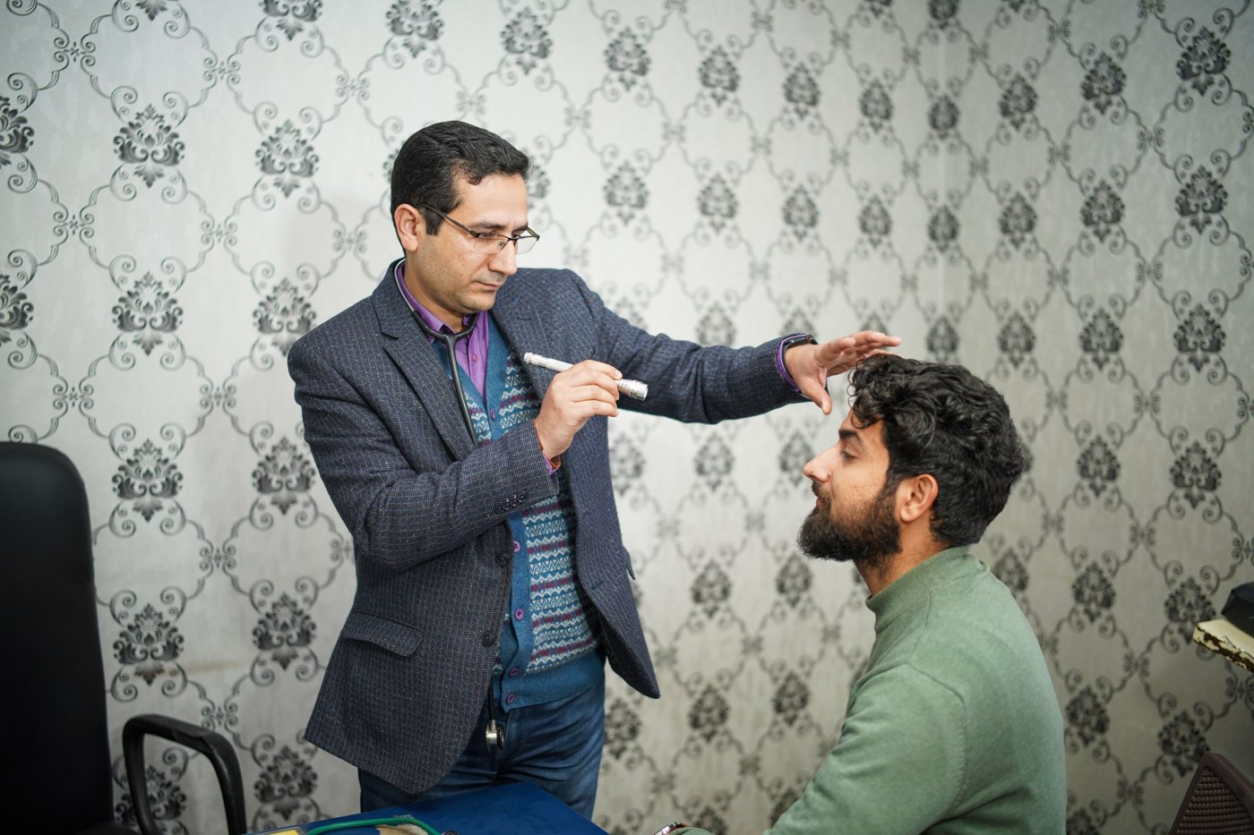 A doctor performing an eye examination on a patient in a clinical setting